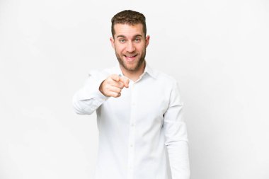 Young handsome blonde man over isolated white background surprised and pointing front