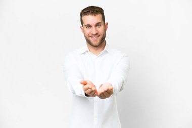 Young handsome blonde man over isolated white background holding copyspace imaginary on the palm to insert an ad