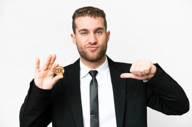 Young business blonde man holding a Bitcoin over isolated white background proud and self-satisfied