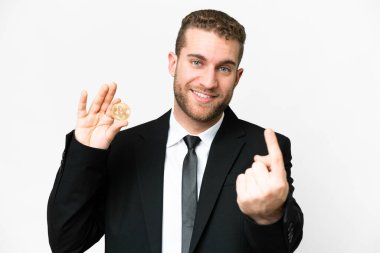 Young business blonde man holding a Bitcoin over isolated white background doing coming gesture