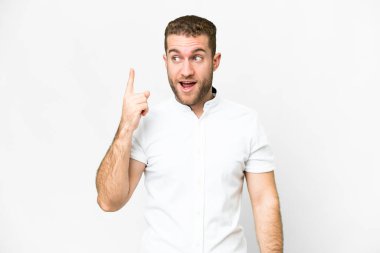 Genç, sarışın, soyutlanmış beyaz arka planda bir parmağını kaldırarak çözümü bulmaya çalışan bir adam.