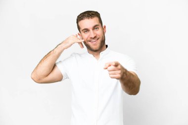 Young handsome blonde man over isolated white background making phone gesture and pointing front
