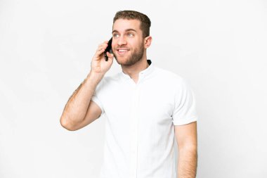Young handsome blonde man over isolated white background keeping a conversation with the mobile phone