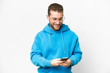Young handsome blonde man over isolated white background sending a message with the mobile