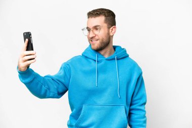 Young handsome blonde man over isolated white background making a selfie