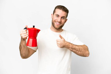 Young handsome blonde man holding coffee pot over isolated white background with thumbs up because something good has happened