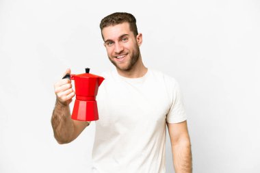 Young handsome blonde man holding coffee pot over isolated white background with happy expression