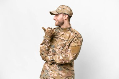 Military man over isolated white background pointing to the side to present a product
