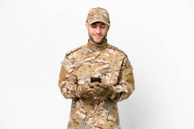 Military man over isolated white background sending a message with the mobile