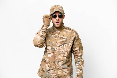 Military man over isolated white background with glasses and surprised