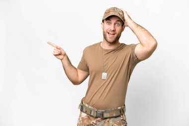 Military with dog tag over isolated white background surprised and pointing finger to the side