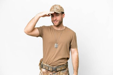 Military with dog tag over isolated white background looking far away with hand to look something