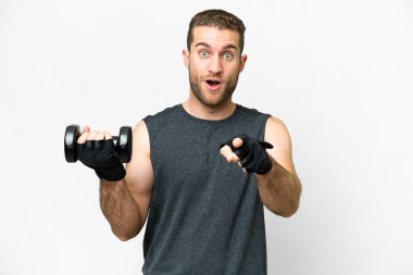 Young sport man making weightlifting over isolated white background surprised and pointing front