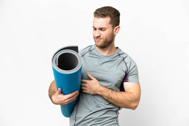 Young sport man going to yoga classes while holding a mat over isolated white background with sad expression