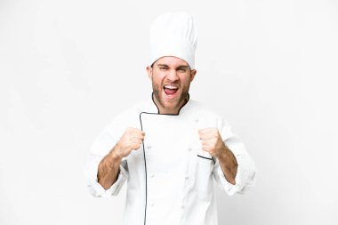 Young blonde man Chef over isolated white background celebrating a victory in winner position