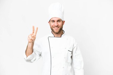 Young blonde man Chef over isolated white background smiling and showing victory sign