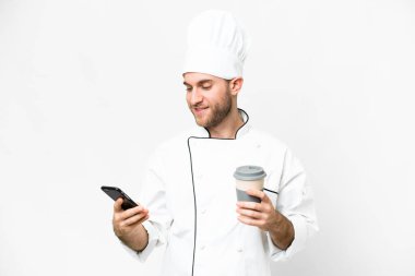 Sarışın genç adam. Şef izole edilmiş beyaz arka plan. Elinde kahve ve cep telefonu var.