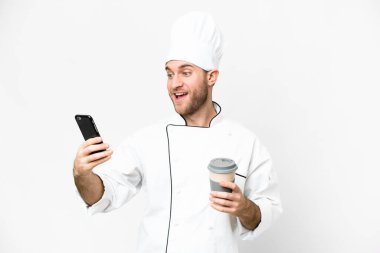 Sarışın genç adam. Şef izole edilmiş beyaz arka plan. Elinde kahve ve cep telefonu var.
