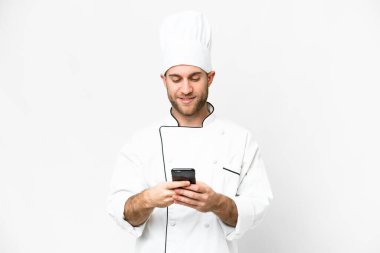 Genç sarışın adam, Şef izole edilmiş beyaz arka plan, cep telefonuyla bir mesaj gönderiyor.