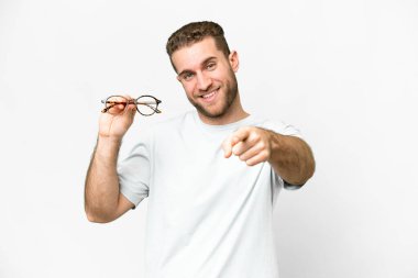 Young handsome blonde man with glasses over isolated white background points finger at you with a confident expression
