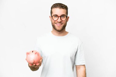 Young handsome blonde man holding a piggybank smiling a lot
