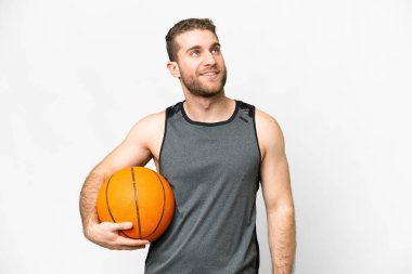 Handsome young man playing basketball over isolated white background thinking an idea while looking up