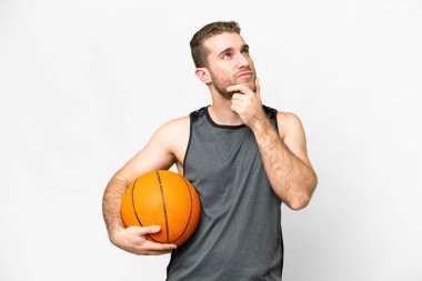 Handsome young man playing basketball over isolated white background having doubts