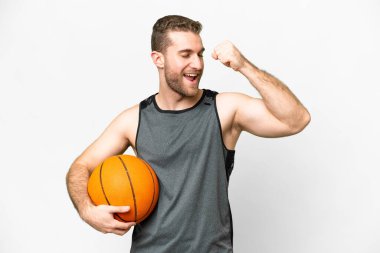 Handsome young man playing basketball over isolated white background celebrating a victory