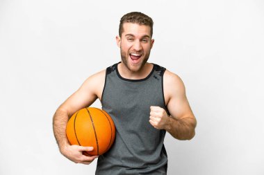 Handsome young man playing basketball over isolated white background celebrating a victory in winner position