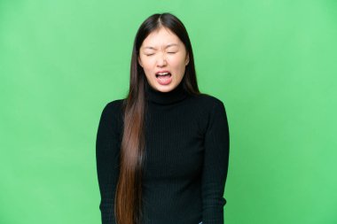 Young Asian woman over isolated chroma key background shouting to the front with mouth wide open