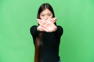 Genç Asyalı kadın izole edilmiş krom anahtar geçmişi var. Bir hareketi durdurmak için eliyle jest yapıyor.