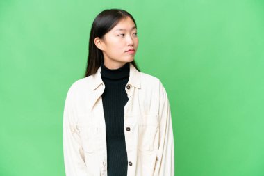 Young Asian woman over isolated chroma key background looking to the side