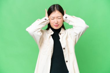 Genç Asyalı kadın izole edilmiş krom anahtar arka planı hayal kırıklığına uğramış ve kulaklarını kapatmış.