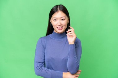 Genç Asyalı kadın izole edilmiş krom anahtar geçmişi ile gülüyor.