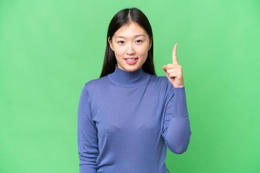 Young Asian woman over isolated chroma key background pointing up a great idea