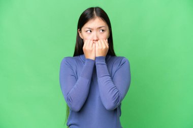Young Asian woman over isolated chroma key background nervous and scared putting hands to mouth