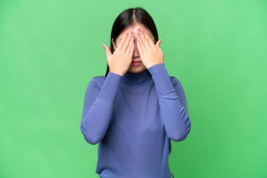 İzole edilmiş krom anahtar geçmişi olan genç bir Asyalı kadın gözlerini elleriyle kapatıyor.