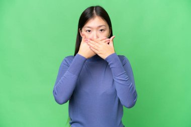 Young Asian woman over isolated chroma key background covering mouth with hands