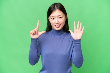Young Asian woman over isolated chroma key background counting seven with fingers