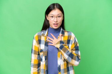 Young Asian woman over isolated chroma key background surprised and shocked while looking right