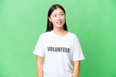 Young volunteer woman over isolated chroma key background thinking an idea while looking up