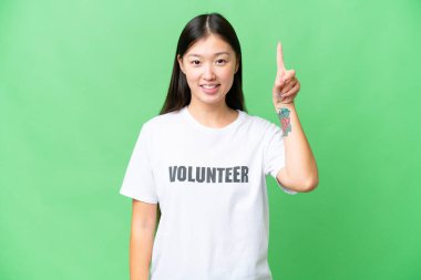 Young volunteer woman over isolated chroma key background pointing up a great idea