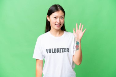 Young volunteer woman over isolated chroma key background saluting with hand with happy expression