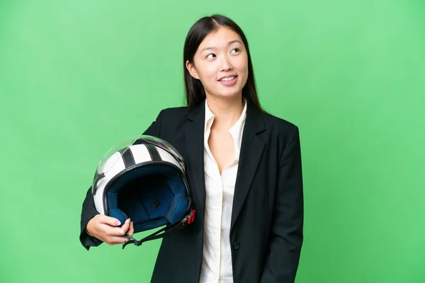 若いですアジアの女性とともにオートバイヘルメット上の隔離されたクロマキー背景考えますAアイデアながら見上げます — ストック写真