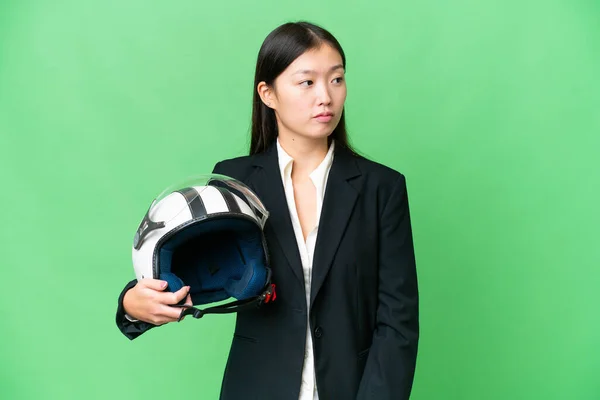若いですアジアの女性とともにオートバイヘルメット上の隔離されたクロマキー背景見ますザ側 — ストック写真