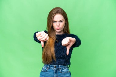 Genç, güzel bir kadın, izole edilmiş krom anahtar arka planda baş parmağının iki eliyle aşağıda olduğunu gösteriyor.