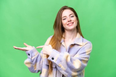 Genç, güzel bir kadın, izole edilmiş bir krom anahtar arka planda, bir reklam koymak için avuç içi hayali bir şey tutuyor.