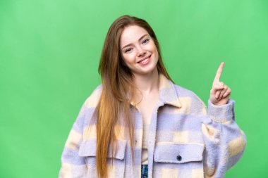 Young pretty woman over isolated chroma key background showing and lifting a finger in sign of the best