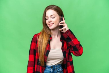 Young pretty woman over isolated chroma key background keeping a conversation with the mobile phone with someone