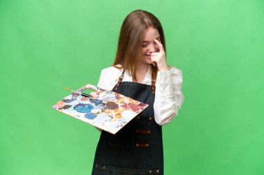 Young artist woman holding a palette over isolated chroma key background laughing